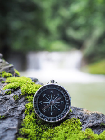 Compass on the rock with waterfall as background. The concept of world tourism day, Searching the...