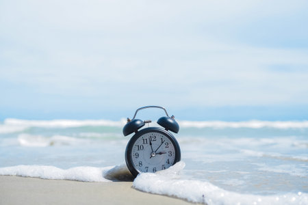 Black alarm clock on the beach with ocean waves. The concept about Time to summer, Travel, Vacation and Relaxationの写真素材
