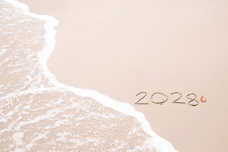 2028 year handwritten with ocean waves on a sandy beach. New Year 2028 conceptの写真素材