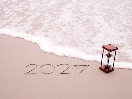 Hourglass, Handwritten inscription 2027 on the beach with ocean waves. The concept of countdown to Happy New Year 2027の写真素材