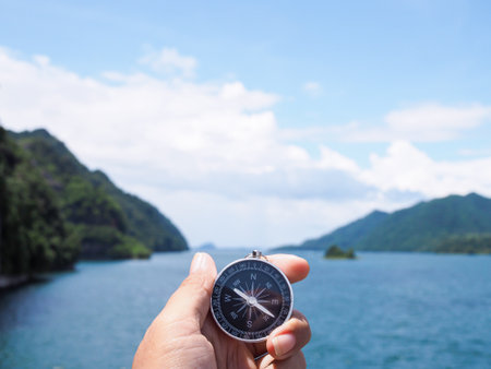 Close up of compass in woman hand with nature as background. The concept of world tourism day, Searching the right directions and Travelの写真素材