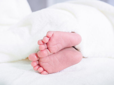 Close up of newborn baby feet on white blanketの写真素材