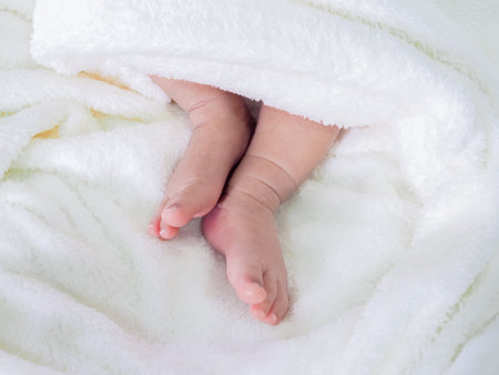 Close up of newborn baby feet on white blanketの写真素材
