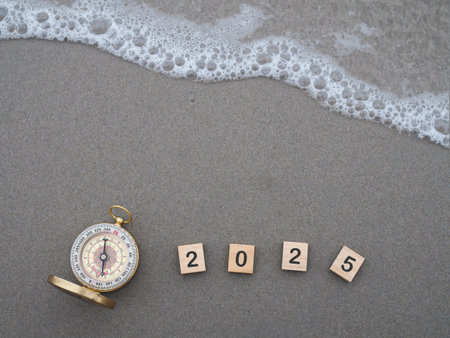 Wooden blocks with the number 2025 and Compass on the beach with ocean waves. The concept of world tourism day, Searching the right directions and Travel in year 2025の写真素材