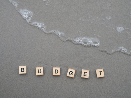 Wooden blocks with the word BUDGET on the beach with ocean waves. The concept about budget planning and allocationの写真素材