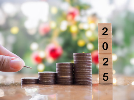 Close up hand putting coin to stack of coins and number 2025 with Christmas light bokeh background....