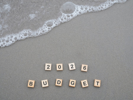 Wooden blocks with the word 2026 BUDGET on the beach with ocean waves. The concept about budget planning and allocation in year 2026の写真素材
