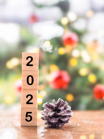 Wooden block number 2025 and pinecones with Christmas light bokeh background. Merry Christmas and Happy New Year 2025の写真素材