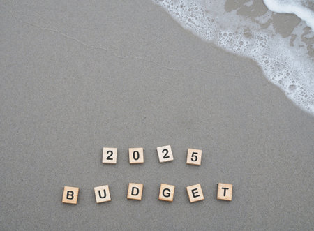 Wooden blocks with the word 2025 BUDGET on the beach with ocean waves. The concept about budget planning and allocation in year 2025の写真素材