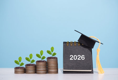 2026 Desk calendar with graduation hat and plants growing up on stack of coins. The concept of...