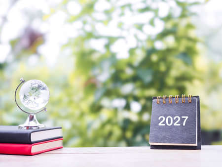 Student creative desktop, Glass earth globe on hardcover book and 2027 desk calendar. Copy space for text, Back to school, Education conceptの写真素材