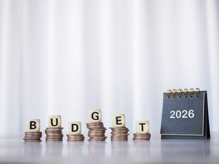 2026 desk calendar and Wooden blocks with the word BUDGET on stack of coins. The concept about...