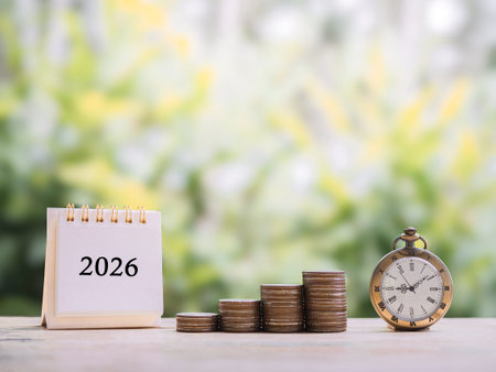 Vintage watch, 2026 desk calendar and stack of coins. The concept of saving money for manage time to...