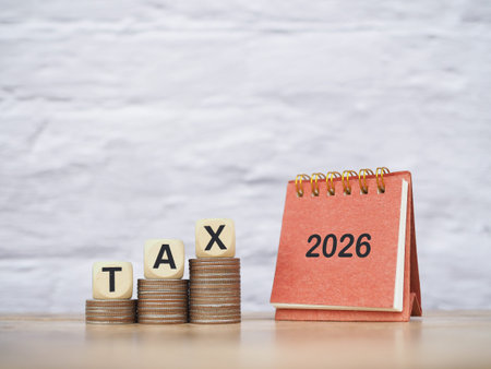 2026 desk calendar, Wooden blocks with the word TAX on stack of coins. The concept about saving...