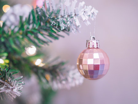 Close-up of shiny pink Christmas ball hanging on Christmas tree with Christmas light backgroundの写真素材
