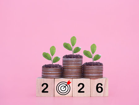 Wooden blocks with the number 2026 and plants growing up on stack of coins. The concept of saving...