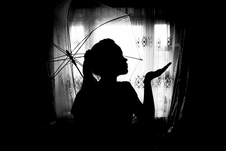 silhouette of a girl  with  an umbrella against the windowの写真素材