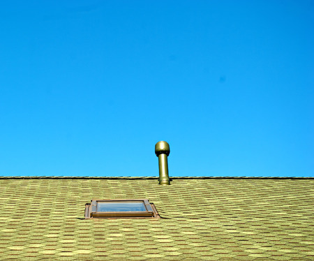 roof window and a chimney on blue skyの写真素材