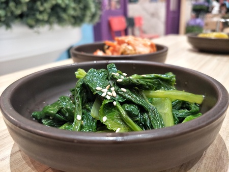 vegetables stir-fried with sesame oil topped sesame on the table with blurred backgroundの写真素材