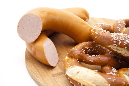 Salted pretzel with sausage on wooden plateの写真素材