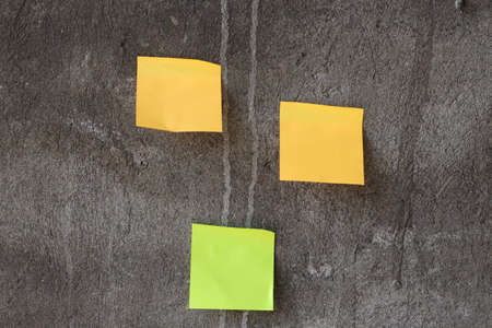 Yellow and green sticky notes papers handing on the gray wall. Horizontal imageの写真素材