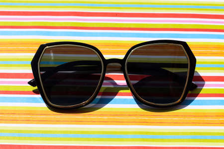 Modern black sunglasses on a bright colorful striped background under the sun. Trendy fashion styleの写真素材