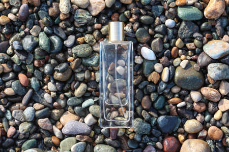 Clear perfume bottle laying on the wet stones. Idea for men cologne or perfume for brutal men, fresh scentedの写真素材