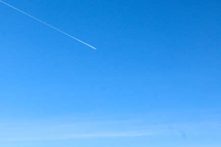 Clear blue sky with slightly visible plane exhaust . Idea for summer spring backgroundの写真素材