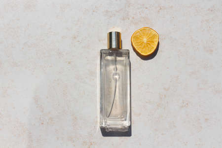 Minimalistic flat lay composition of a perfume bottle for mock up. A clear glass bottle with a slice of fresh lemon. Idea for citrus scented perfume advertisementの写真素材