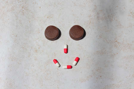 Smiling face of pills and brown tablets to protect from fleas for cats and dogs. Tablets on a neutral backgroundの写真素材