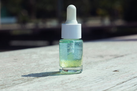 Beauty product bottle with a dropper outside on a neutral background outside on a sunny day.
