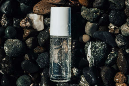 Close up of a beauty product transparent bottle on wet beach stones . Fresh ocean scented product mock up.の写真素材