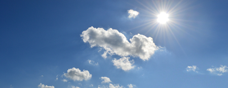 bright blue sky with clouds and sun shiningの写真素材