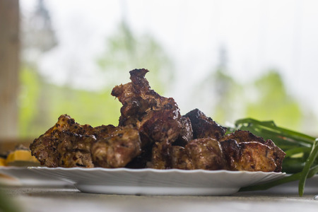 Ready to shish kebab on a snow-white plate Side view on a table with white wooden boardsの写真素材