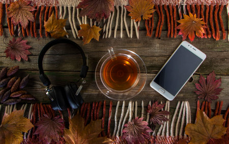 A cup of tea and a mobile phone on a vintage wood background.