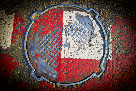 Red white sewer hatch with rubbed paintの写真素材