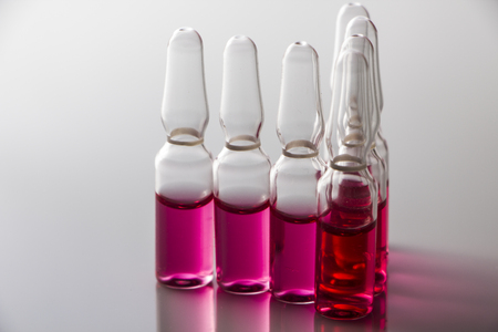 Medical vial with red contents isolated on whiteの写真素材