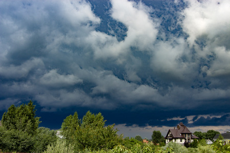 Heavy, stormy clouds of contrasting color over the evening city backgroundの写真素材