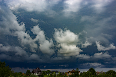 Heavy, stormy clouds of contrasting color over the evening city backgroundの写真素材