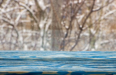 blue wooden window sill, with a winter landscape outside the window.の写真素材