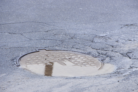 Pothole in asphalt near the sewer hatch, in the middle of the streetの写真素材