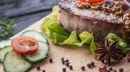Fried veal steak and lettuce leaf, spices. On a wooden tableの写真素材