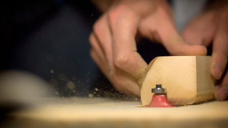 A large plan, hands of an artisan working on a wooden part.