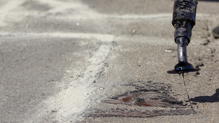 Workers repair the road, pour small cracks with bitumen to prevent further destruction of the road surface. Close upの写真素材