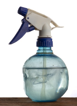 Old blue plastic water bottle with spray, on a wooden table top and white background. close upの写真素材