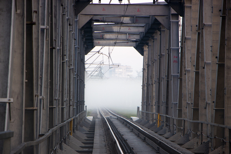 A railway bridge in the morning fog or smoke through which the rays of the sun shineの写真素材