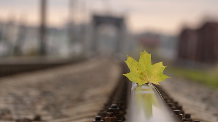 Yellow maple leaf on old rusty rails. Concept of loneliness and the onset of autumn.の写真素材