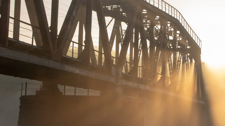 A railway bridge in the morning fog or smoke through which the rays of the sun shine background.