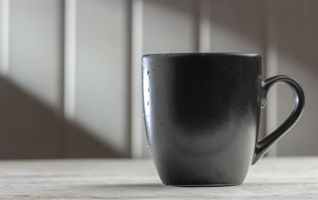 Ceramic Black mug with patterns on a white wooden table, in the morning sun rays close upの写真素材