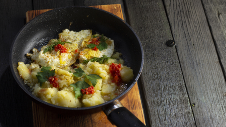 Homemade Fried Potatoes and Omelettes in a Frying Pan. On an old black wooden table close upの写真素材